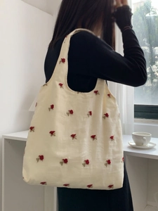 Canvas tote bag with red floral embroidery for commuting shown in a bright lifestyle setting