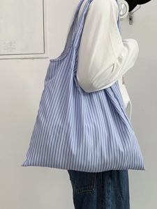 Vue détaillée latérale d'un grand sac cabas en toile à rayures bleues porté par un mannequin