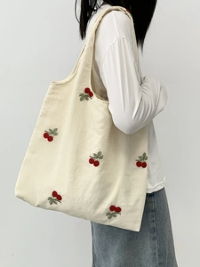 Close-up of a large canvas tote bag featuring intricate red cherry floral embroidery