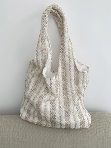 Detailed close-up of large white hollow-out knit tote bag with vibrant neon colored spots