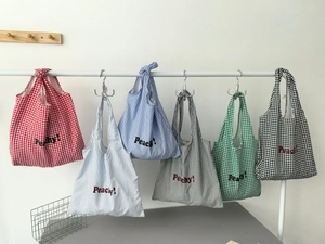 Detail of colorful striped and checkered nylon tote bags with Peachy text print