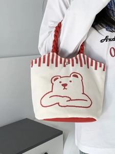 Detail of small canvas tote bag with red handles and cute cartoon bear print decoration