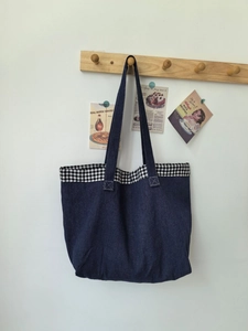 Détail d'un sac cabas en jean avec bordure à carreaux vichy et coutures renforcées