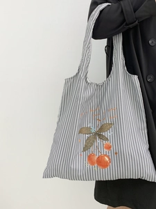 Close-up of striped canvas tote bag featuring cherry print and artistic text on side