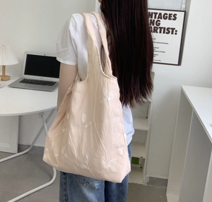 Close-up of pink tote bag with white floral embroidery and spacious interior design