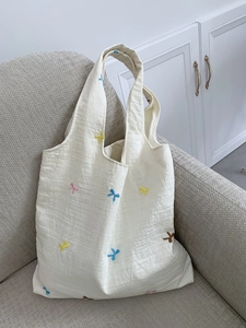 Detailed texture of beige canvas tote with colorful floral embroidery on a soft sofa