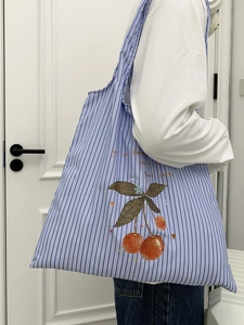Detail of blue and white striped canvas tote with red cherry print and artistic text