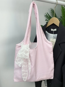 Close-up of pink striped canvas tote bag with a white crocheted lace bow detail