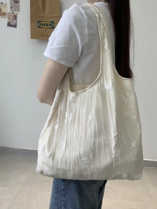 Detail of elegant lace embroidery with butterfly and leaf patterns on beige tote bag