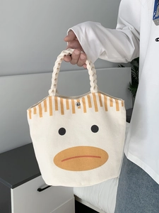 Detail of canvas tote bag showing the woven handle, metal snap button, and cartoon duck print