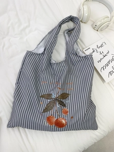 Detail of striped canvas tote bag with cherry print and text on a white sheet