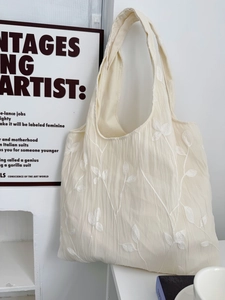 Detailed close-up of delicate leaf embroidery on a cream-colored lace tote bag