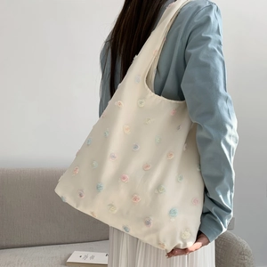 Detailed view of cream canvas tote bag featuring colorful 3D floral embroidery decorations