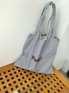 Detail of striped canvas tote bag featuring Peachy! red letter print and thick texture