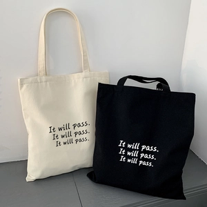 Detail minimalistischer Segeltuchtaschen in Schwarz und Weiß mit wiederholtem Buchstabendruck