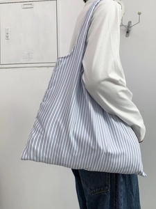 Grand sac cabas en toile à rayures bleues et blanches porté avec un style décontracté