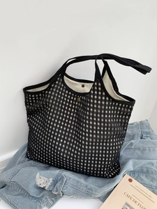 Detail of black and white checkered mesh tote bag with metal snap and fabric handles