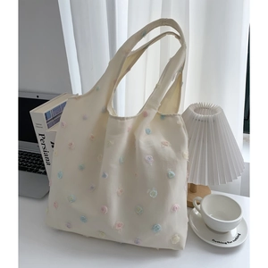 Close-up of cream canvas tote bag featuring delicate 3D embroidered floral decorations