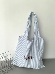 Close-up of blue striped canvas tote bag featuring red Peachy! embroidery and sturdy handles