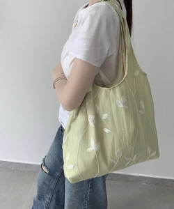 Detail of light green floral embroidered canvas tote bag worn with casual white t-shirt