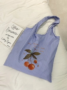 Detail of blue striped canvas tote bag featuring a cherry print and stylish calligraphy