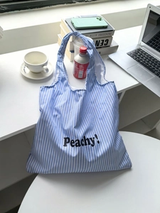 Close-up of blue and white striped tote bag with Peachy! lettering in a lifestyle setting