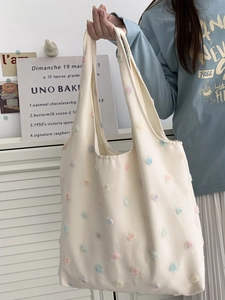 Close-up of white canvas tote bag with colorful 3D floral embroidery and soft fabric texture