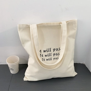 Detail der minimalistischen cremefarbenen Canvas-Tasche mit wiederholtem Textdruck