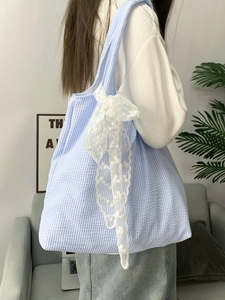 Blue and white seersucker tote bag detail with lace bows shown on a female model