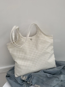 Close-up of minimalist checkered canvas bag showing silver snap button and fabric texture