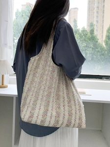 Detailed texture of neon striped knit canvas tote bag on female model's shoulder