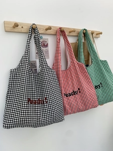 Three minimalist plaid canvas tote bags in black, red, and green with Peachy print
