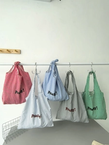 Detail shot of five striped and checkered nylon tote bags with Peachy lettering