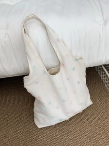 Detail of floral embroidery on cream canvas tote bag with 3D colorful blossom accents