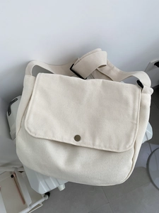 Detailed view of cream canvas messenger bag with vintage metal buckle and wide strap