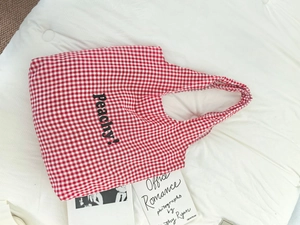 Detail shot of the red and white checkered canvas tote bag with black Peachy text