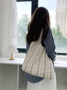 Detail of large colorful knit tote bag worn as a shoulder bag in a modern room setting