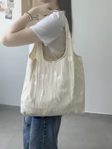 Detailed side view of an off-white lace canvas tote bag featuring floral embroidery texture