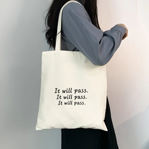 Detail einer weißen Stofftasche aus Segeltuch mit schwarzem Schriftzug und Schultergurt