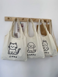 Détail de sacs en toile avec imprimés animaux mignons suspendus à des crochets en bois