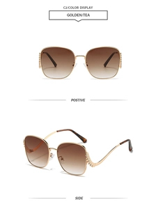 Close-up of golden metal sunglasses with tea gradient lenses and rhinestone temple details