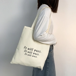Nahaufnahme der beigen Canvas-Tragetasche mit schwarzem 'It will pass' Schriftdruck