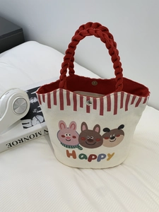 Close-up of small canvas tote with red woven handles and cute cartoon animal print