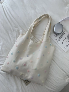 Cream canvas tote bag with 3D colorful floral embroidery in a minimalist aesthetic