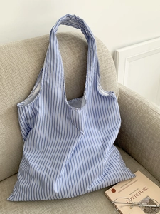 Gros plan d'un sac cabas en tissu à rayures bleues posé sur un canapé minimaliste