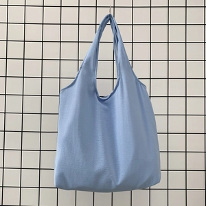 Detail view of a soft light blue canvas tote bag showing textured cotton fabric and large capacity