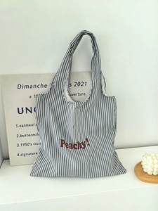 Detail of striped nylon tote bag featuring red Peachy! print and minimalist pattern