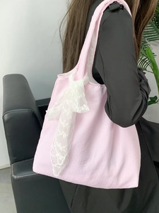 Detail of pink and white striped canvas tote bag featuring a decorative lace bow