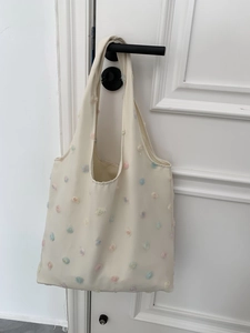 Detail of colorful floral 3D embroidery on cream canvas tote bag with soft fabric texture
