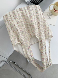 Detailed knit texture of a colorful striped tote bag hanging on a modern white chair